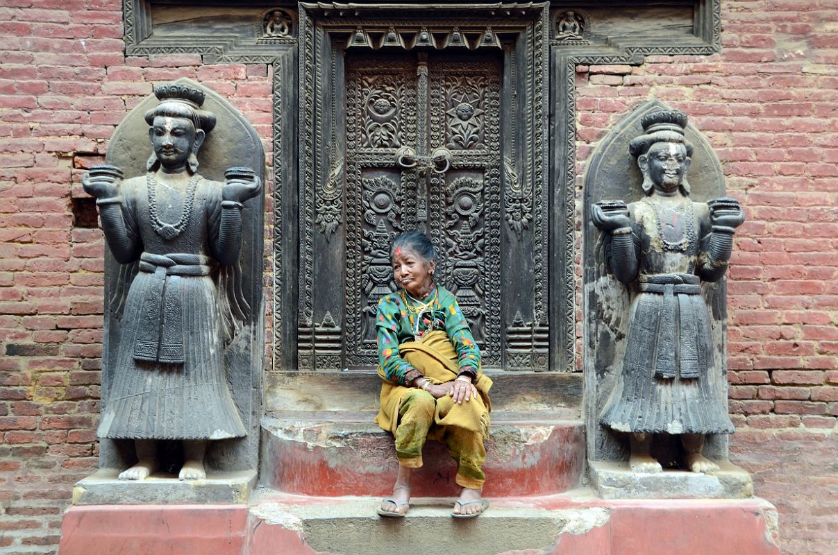 Kathmandu Bhaktapur 04-6 A Woman Sits Peacefully Between Two Statues In Taleju Chowk Just Inside The Golden Gate A woman sits peacefully between two statues in the Taleju Chowk just inside the Golden gate in Bhaktapur.